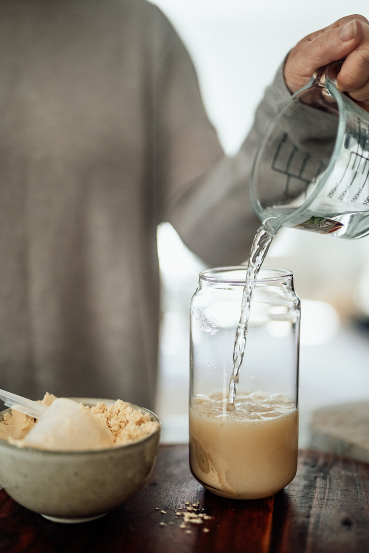 drink being poured from above into a clear, double-walled glass cup