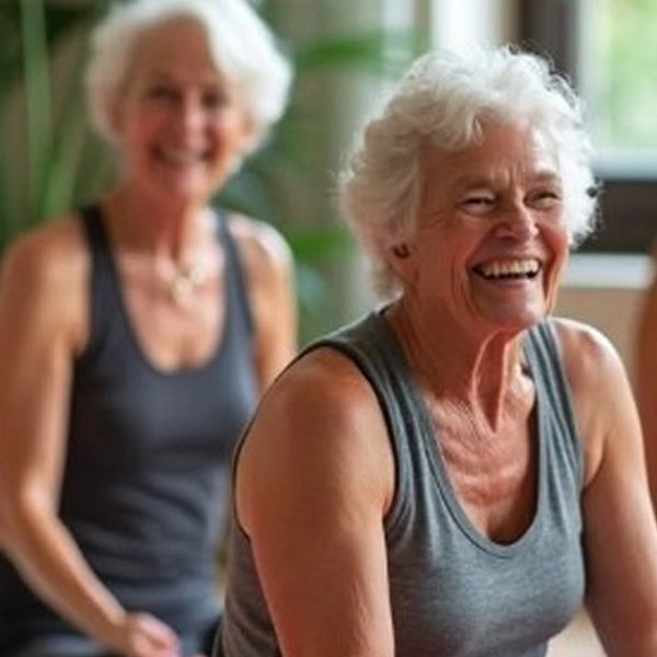 A close-up shot focusing on an older woman with white, curly hair wearing a grey tank top, laughing joyfully with her eyes crinkled