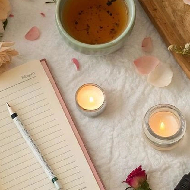 A flat-lay view of a relaxation or journaling station on a white textured surface